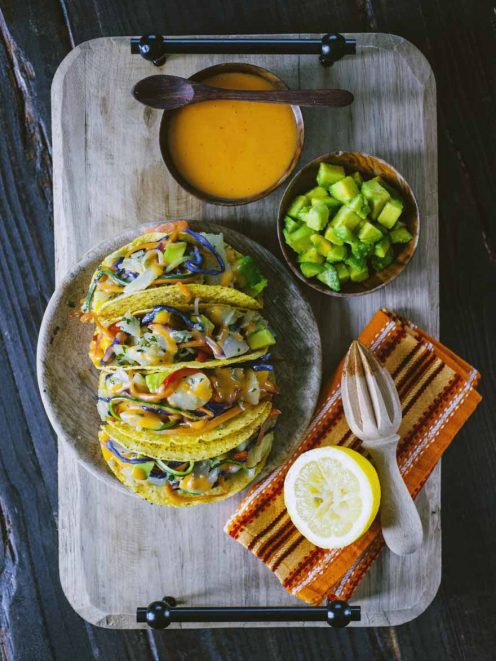 Tacos con stoccafisso e verdure sfilacciate, conditi con maionese al pomodoro e serviti con avocado a cubetti