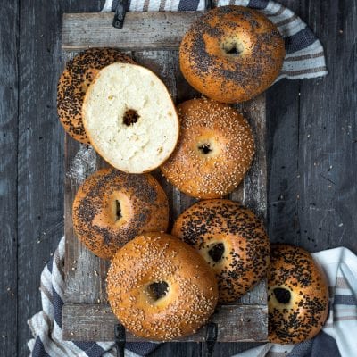 Bagel appena sfornati con semi di sesamo e papavero, uno tagliato a metà