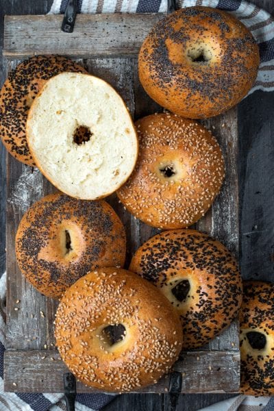 Bagel appena sfornati con semi di sesamo e papavero, uno tagliato a metà