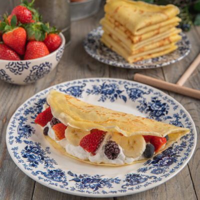 Crepes senza glutine farcite con panna, fragole, banana e frutti di bosco