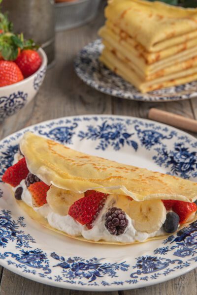 Crepes senza glutine farcite con panna, fragole, banana e frutti di bosco