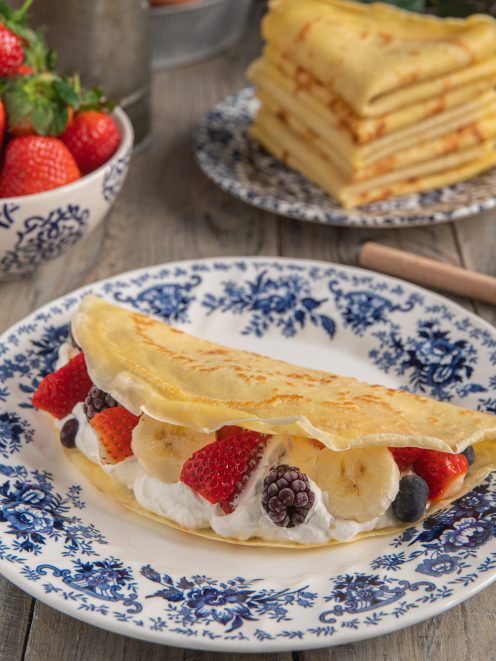 Crepes senza glutine farcite con panna, fragole, banana e frutti di bosco