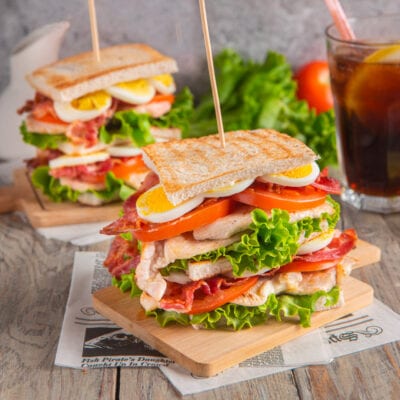 Club sandwich a strati con pollo, bacon croccante, uovo sodo, pomodoro e lattuga farcito tra fette di pane tostato