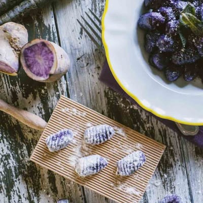 Gnocchi di patate e carote viola rigati, crudi sul rigagnocchi e cotti nel piatto con salvia