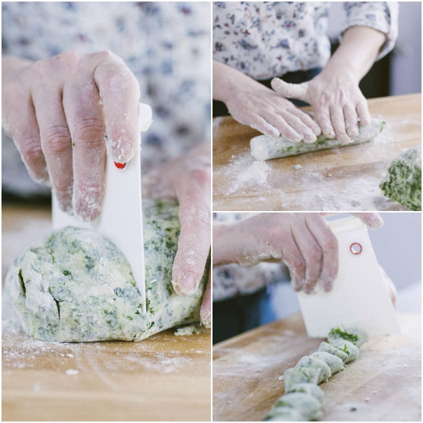 Mani che tagliano e arrotolano l'impasto verde agli spinaci per formare gli gnocchi