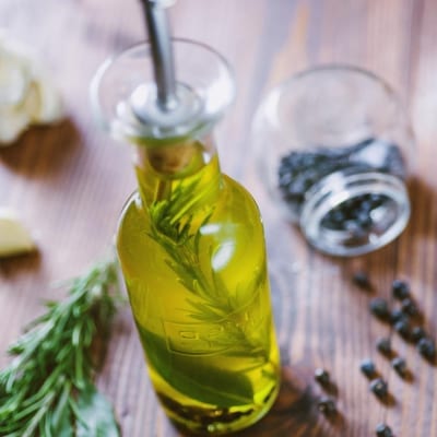 Olio aromatizzato per carne con rametti di rosmarino e grani di pepe nero