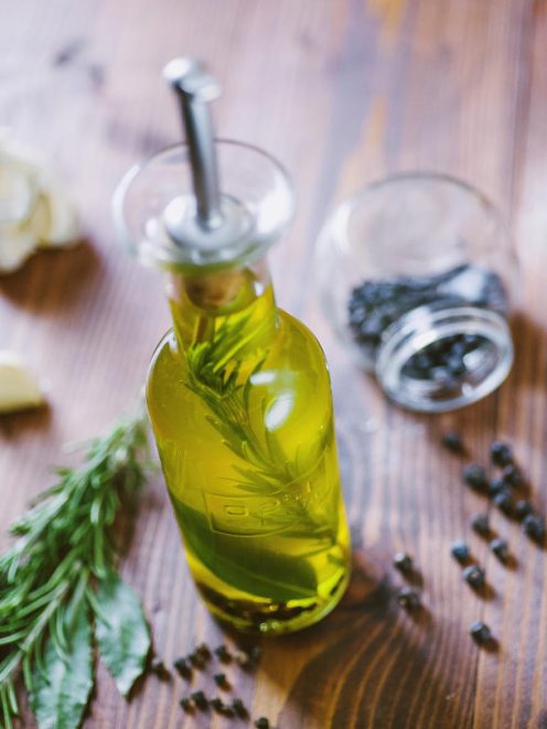 Olio aromatizzato per carne con rametti di rosmarino e grani di pepe nero