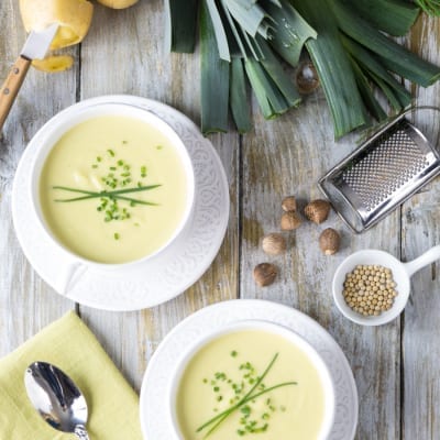 Vichyssoise servita in due ciotole, vellutata di patate e porri guarnita con erba cipollina