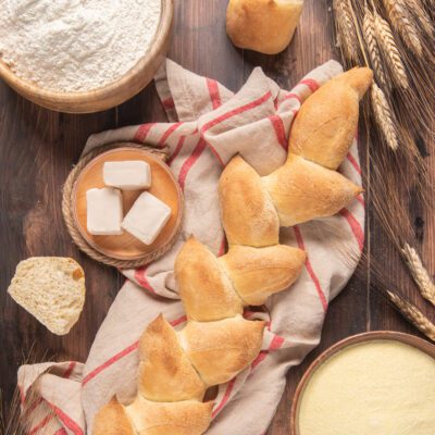 Spiga di pane dorata con crosta croccante, affiancata da cubetti di lievito e farina
