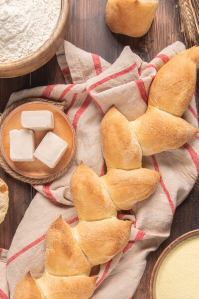 Spiga di pane dorata con crosta croccante, affiancata da cubetti di lievito e farina