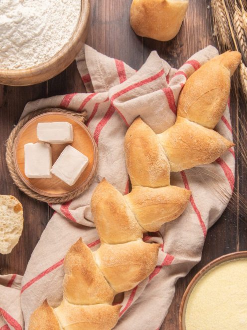 Spiga di pane dorata con crosta croccante, affiancata da cubetti di lievito e farina