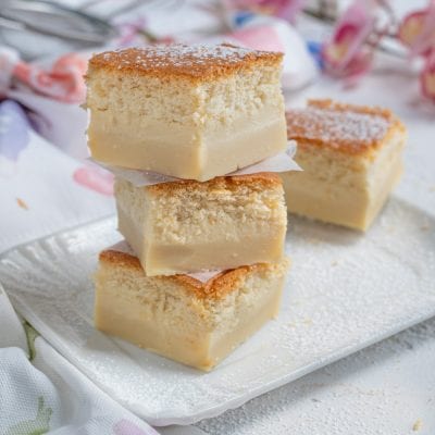 Torta magica a fette impilate con strato di crema e superficie dorata spolverata di zucchero a velo