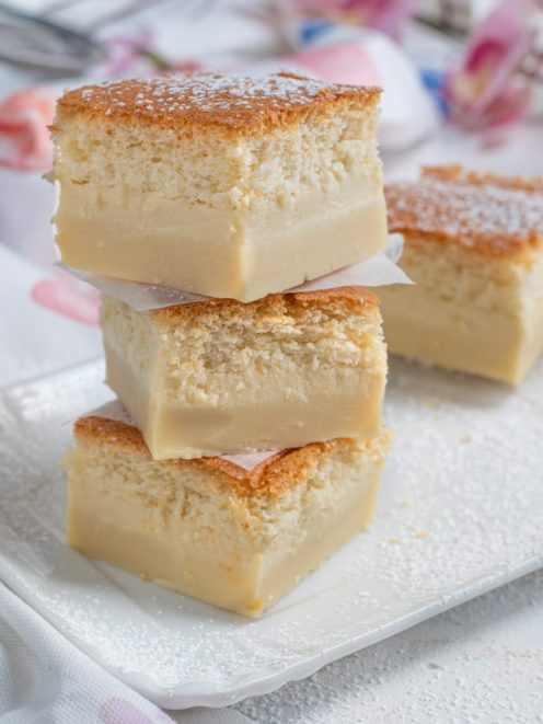 Torta magica a fette impilate con strato di crema e superficie dorata spolverata di zucchero a velo