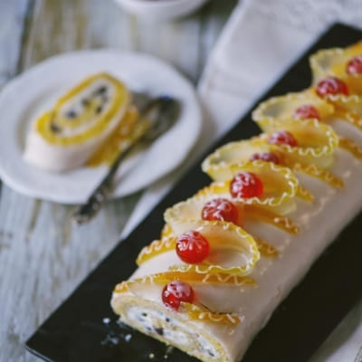 Rotolo di cassata glassato con scaglie di ghiaccia colorata e ciliegine candite in fila