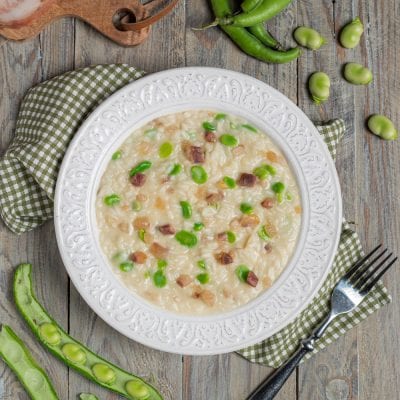 Risotto con fave, guanciale e pecorino cremoso, con fave fresche e cubetti di guanciale ben visibili