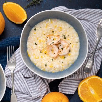 Risotto con gamberi e arancia guarnito con scorza grattugiata e timo fresco