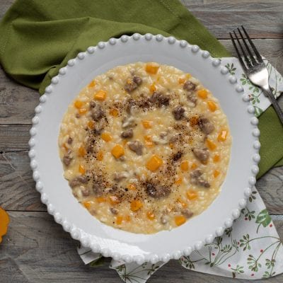 Risotto salsiccia zucca e liquirizia mantecato, con dadini di zucca e pepe nero in superficie