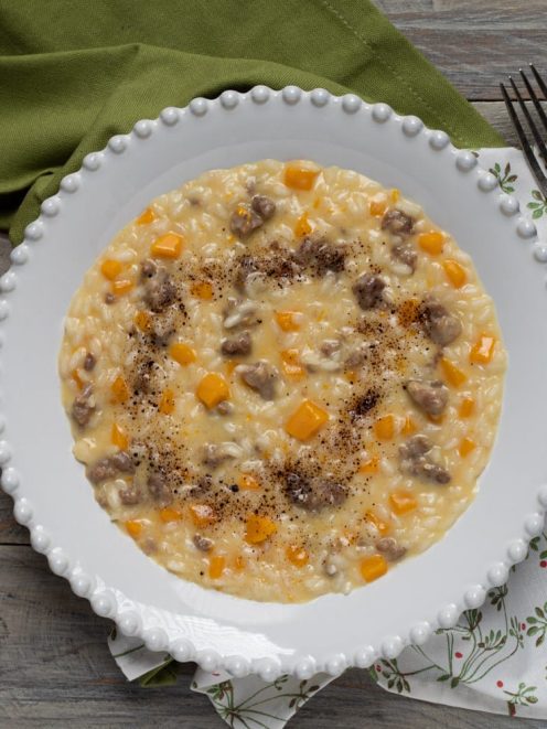 Risotto salsiccia zucca e liquirizia mantecato, con dadini di zucca e pepe nero in superficie