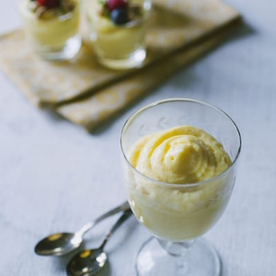 Crema chiboust servita in calici con ciuffo a spirale, guarnita con frutti di bosco freschi