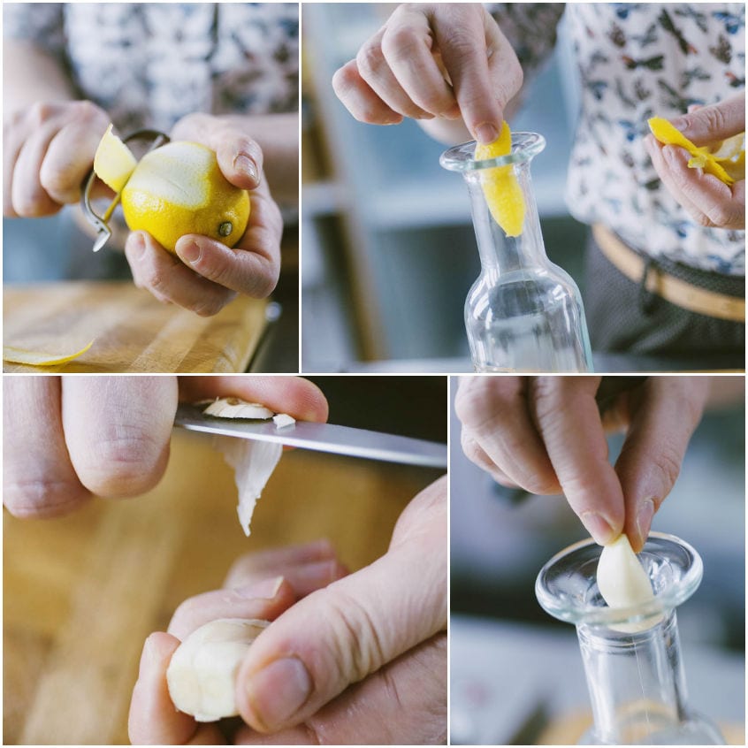 Mani che pelano un limone, inseriscono la scorza e uno spicchio d'aglio in una bottiglietta