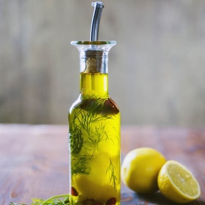 Olio aromatizzato per pesce con aneto e peperoncini rossi, servito in oliera con limone a lato