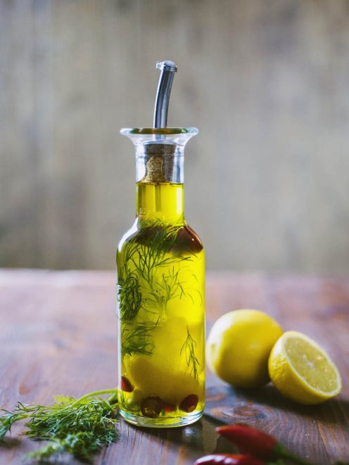 Olio aromatizzato per pesce con aneto e peperoncini rossi, servito in oliera con limone a lato