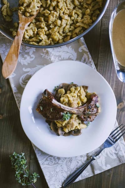 Spätzle con costolette d'agnello e funghi, guarniti con timo fresco