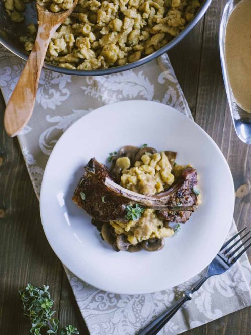 Spätzle con costolette d'agnello e funghi, guarniti con timo fresco