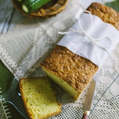 Zucchini bread affettato con mollica verde e crosta dorata, accanto a zucchine fresche