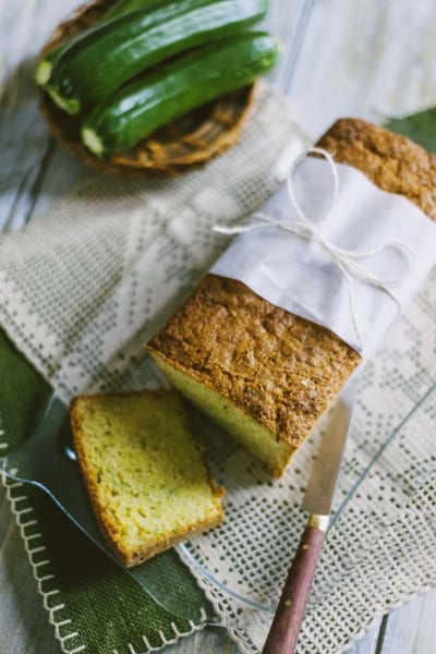 Zucchini bread affettato con mollica verde e crosta dorata, accanto a zucchine fresche