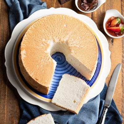 Angel cake con superficie dorata, una fetta tagliata rivela l'interno soffice e bianco