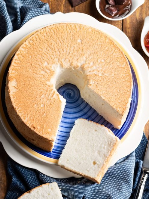 Angel cake con superficie dorata, una fetta tagliata rivela l'interno soffice e bianco
