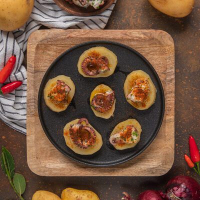 Pulpo a la gallega con fette di patata lessa, paprika affumicata e olio d'oliva in padella di ferro