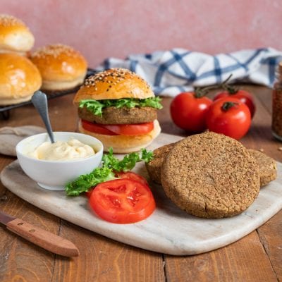 Veggie burger con hamburger vegetale, fette di pomodoro, lattuga e maionese su panino ai semi