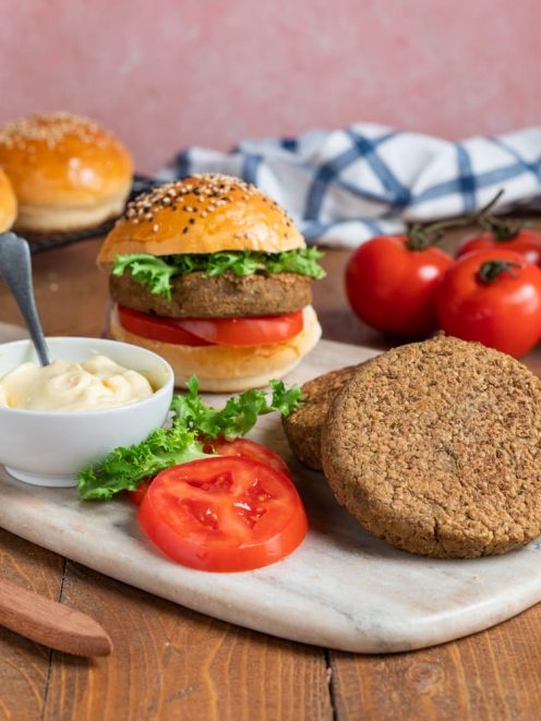 Veggie burger con hamburger vegetale, fette di pomodoro, lattuga e maionese su panino ai semi