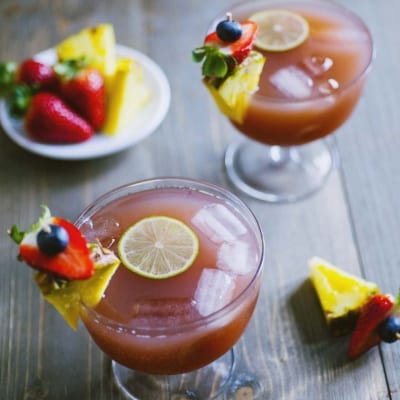 Analcolico alla frutta con ghiaccio, fetta di lime, ananas, fragola e mirtillo sul bordo