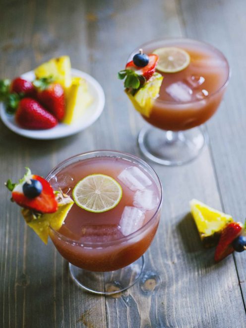Analcolico alla frutta con ghiaccio, fetta di lime, ananas, fragola e mirtillo sul bordo