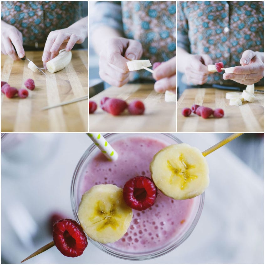 Spiedi di rondelle di banana e lamponi adagiati sul frappè rosa nel bicchiere