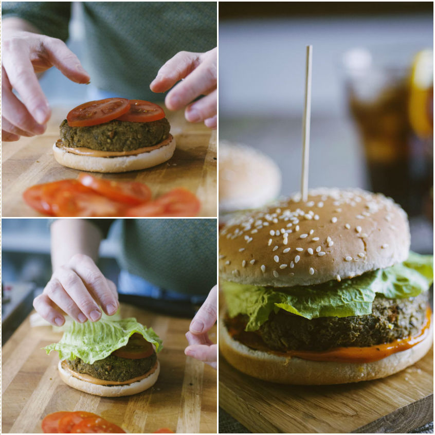 Mani che assemblano un veggie burger con fette di pomodoro e foglia di lattuga sul panino