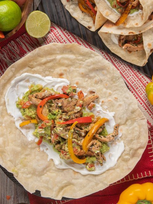Fajitas con pollo grigliato, peperoni saltati, guacamole e panna acida su tortilla aperta