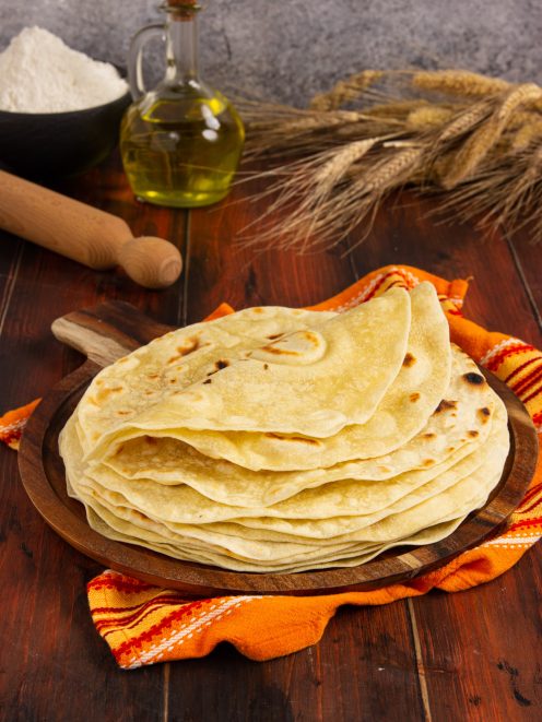 Piadine sottili impilate con macchie di cottura dorate, servite su tagliere