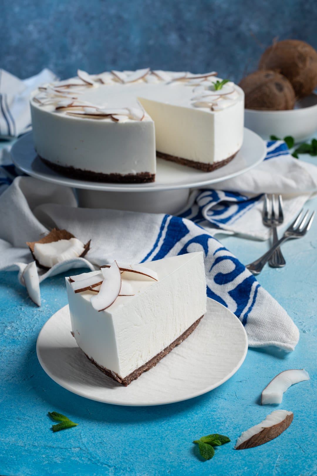 Fetta di cheesecake al cocco con base al cioccolato e lamelle di cocco fresco in cima