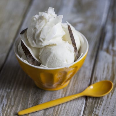 Gelato al cocco servito a palline con scaglie di cocco e guscio di noce di cocco