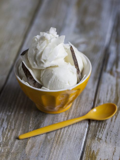 Gelato al cocco servito a palline con scaglie di cocco e guscio di noce di cocco
