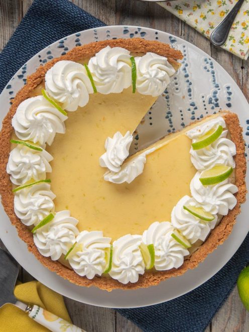Key lime pie con base di biscotto, crema al lime e ciuffi di panna, una fetta già servita