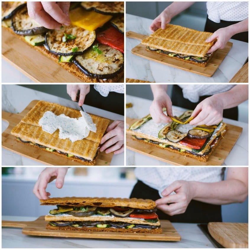 Mani che assemblano la millefoglie di verdure a strati con ricotta, melanzane, zucchine e peperoni