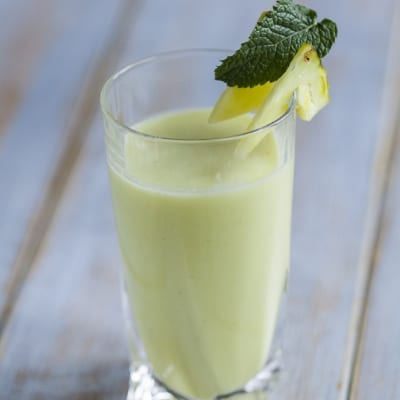 Succo di ananas, cocco, lime e menta fresca servito in bicchiere con guarnizione di menta e ananas