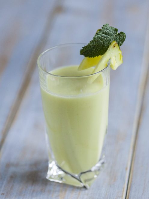 Succo di ananas, cocco, lime e menta fresca servito in bicchiere con guarnizione di menta e ananas