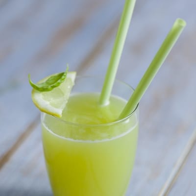 Succo di melone, basilico e limone con fettina di limone sul bordo e cannucce