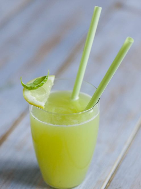 Succo di melone, basilico e limone con fettina di limone sul bordo e cannucce
